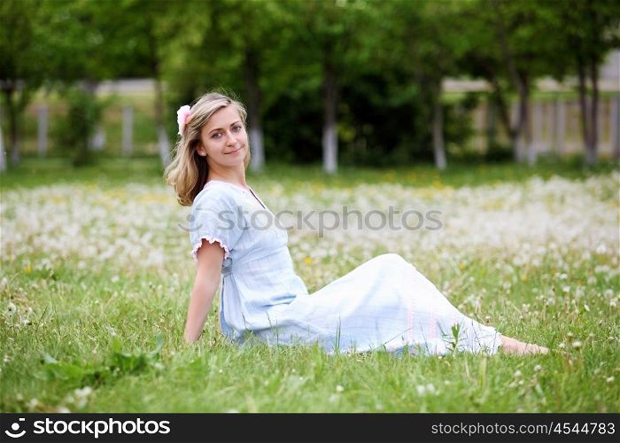Young blond woman in blue dress in the park