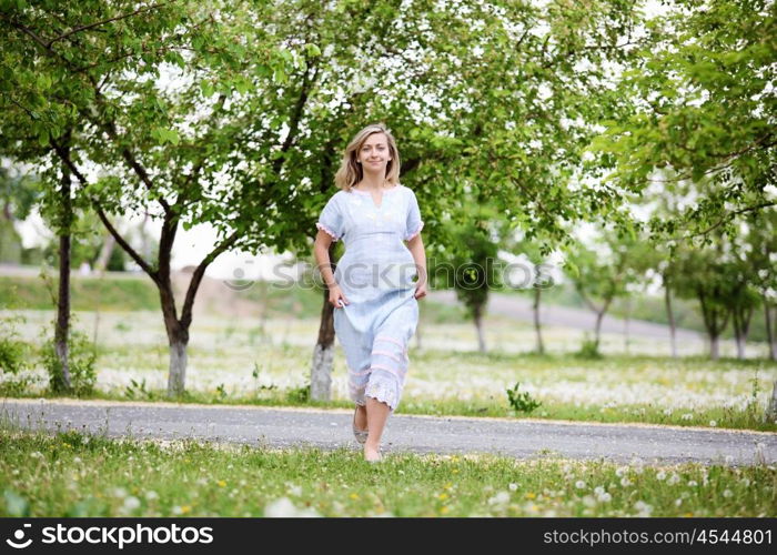 Young blond woman in blue dress in the park