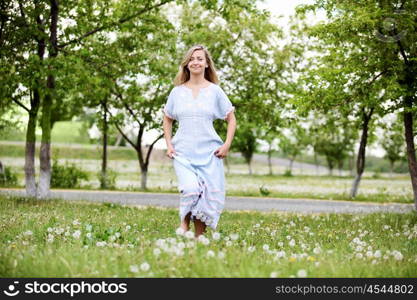 Young blond woman in blue dress in the park