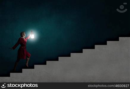 Young blond woman in red cloak with lantern walking in night. Lost in darkness