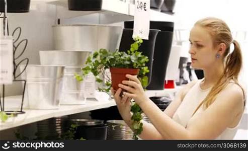 Young blond woman looking at vases and plants in a gardening shop