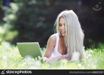 young blond woman lying on grass. young blond woman lying on grass with laptop