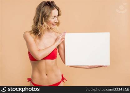 young blond woman red bikini holding blank board