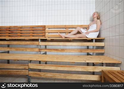 Young blond woman relaxing in sauna