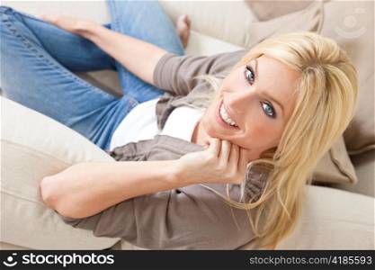 Young Blond Woman Relaxing & Smiling At Home on Sofa