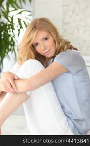 Young blond woman sitting on her bed