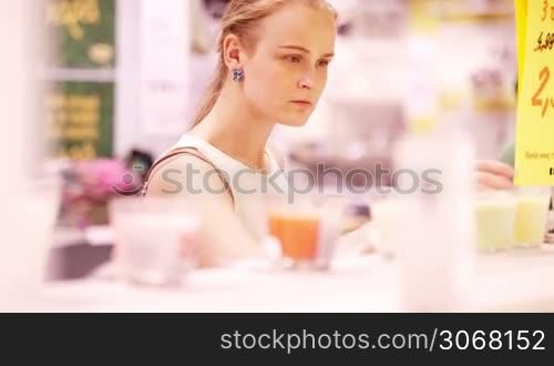 Young blond woman smelling scented candles in the store