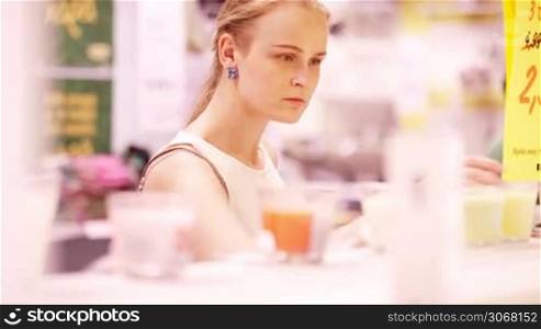 Young blond woman smelling scented candles in the store