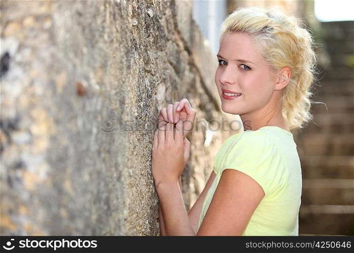 Young blond woman standing against a wall