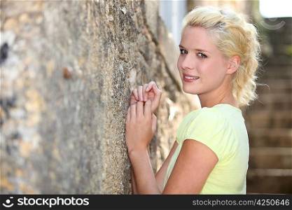 Young blond woman standing against a wall