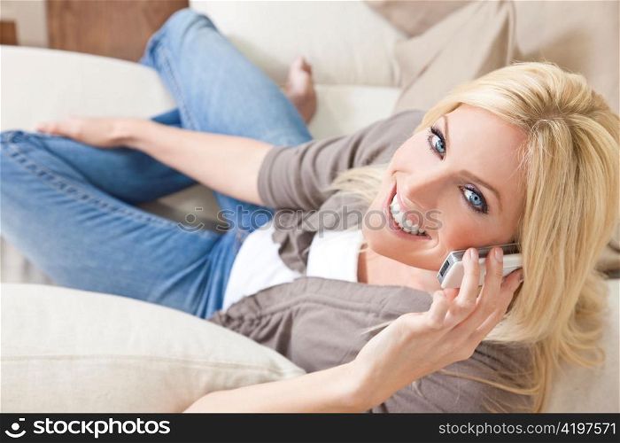 Young Blond Woman Using Cell Phone At Home on Sofa
