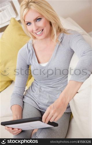 Young Blond Woman Using Tablet Computer At Home on Sofa