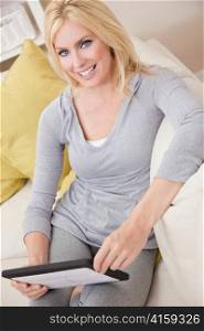 Young Blond Woman Using Tablet Computer At Home on Sofa