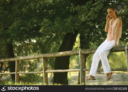 Young blond woman with mobile phone in the park