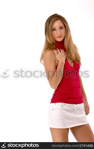 Young blond woman with one hand on her chest. She is wearing a red sleeveless shirt and white mini skirt. Studio shot, isolated on a white background.