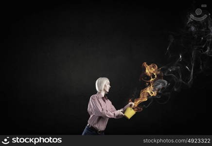 Young blond woman with yellow bucket in hands. Girl splashing fire flames