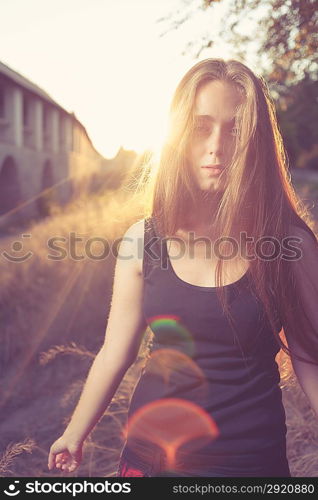 young blond women against gold sunset light. Autumn time. Backlit.Vertical shot with lens flares