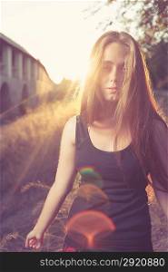 young blond women against gold sunset light. Autumn time. Backlit.Vertical shot with lens flares