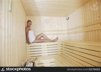 young blonde beautiful woman in finland sauna warming up and healing in a spa wellness resort cabin