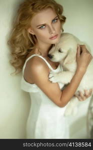 Young blonde beauty hugging a white puppy dog