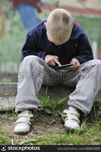 young blonde boy playing videogames outdoor in park