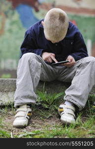 young blonde boy playing videogames outdoor in park