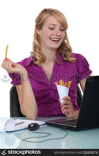 young blonde businesswoman eating fries