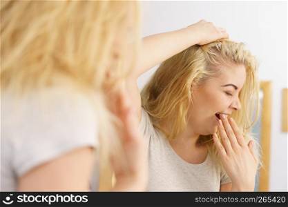 Young blonde female feeling dull and tired after waking up. Woman yawning being sleepy in bathroom.. Woman feeling tired in bathroom