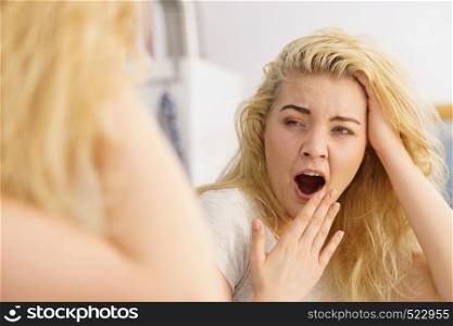 Young blonde female feeling dull and tired after waking up. Woman yawning being sleepy in bathroom.. Woman feeling tired in bathroom
