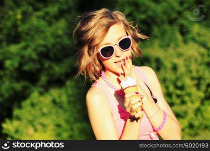 Young blonde hipster girl eating a delicious ice cream in summer hot weather in sunglasses have fun and good mood looking in camera and smiling.