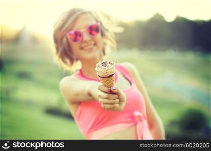 Young blonde hipster girl eating a delicious ice cream in summer hot weather in sunglasses have fun and good mood looking in camera and smiling.