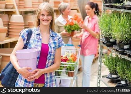Young blonde holding flower pot at garden centre retail store
