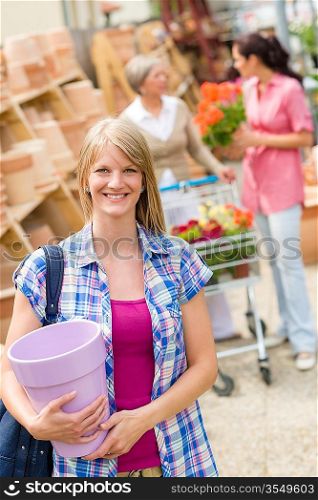 Young blonde holding flower pot at garden centre retail store