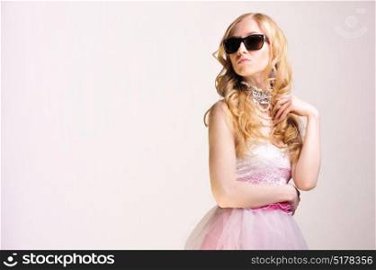 Young blonde model posing with an elegant pink dress