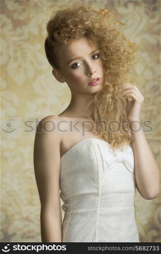 Young, blonde, pretty girl with curly hairstyle. She is wearing white, gorgeous dress with a loop and colorful makeup.