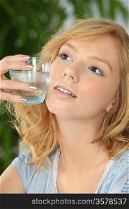 young blonde with glass of water against cheek