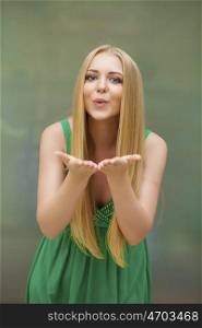 Young blonde woman blowing while sending an air kiss, indoor