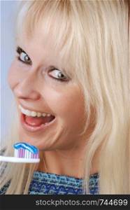 Young blonde woman brushing her teeth. Woman brushing her teeth