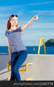 Young blonde woman casual style against stone wall pointing with finger sea in the background