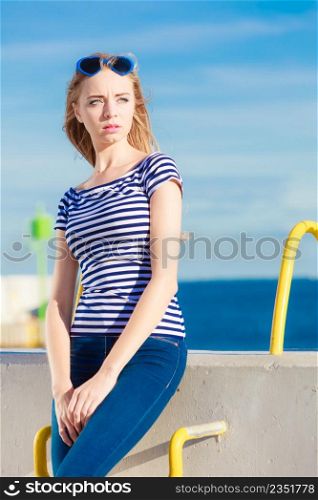 Young blonde woman casual style against stone wall sea in the background