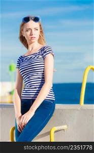 Young blonde woman casual style against stone wall sea in the background