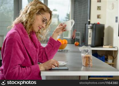 young blonde woman drinks a coffee in the kitchen at morning