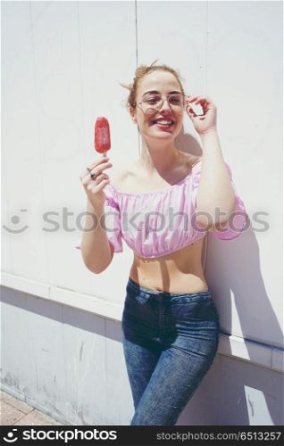 Young blonde woman eating an strawberry ice cream in summer