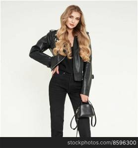 Young blonde woman in black leather jacket and black jeans. Girl posing on a white background. Jewelry and hairstyle. Fashion photo