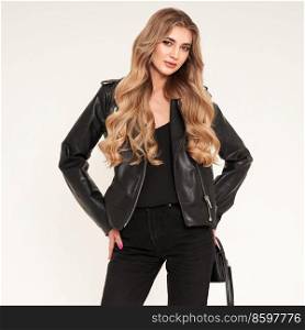 Young blonde woman in black leather jacket and black jeans. Girl posing on a white background. Jewelry and hairstyle. Fashion photo