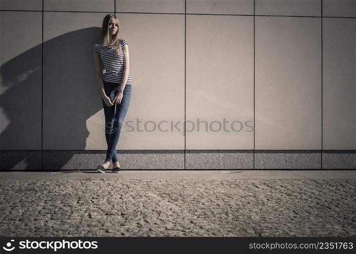 Young blonde woman in full length casual style against stone grunge wall