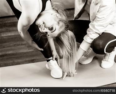 Young blonde woman in sportswear stretching body, working out with her trainer. Training at home, being fit and healthy.. Woman in sportswear doing workout with trainer
