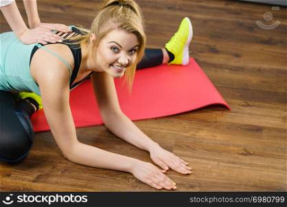 Young blonde woman in sportswear stretching body, working out with her trainer. Training at home, being fit and healthy.. Woman in sportswear doing workout with trainer