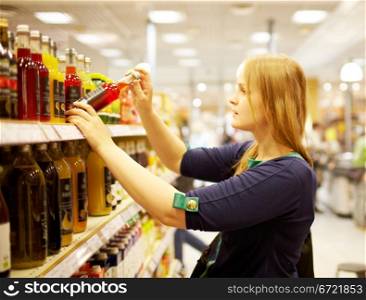 Young blonde woman is choosing juice in the supermarket