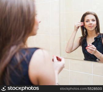 Young blonde woman makes up in front of window